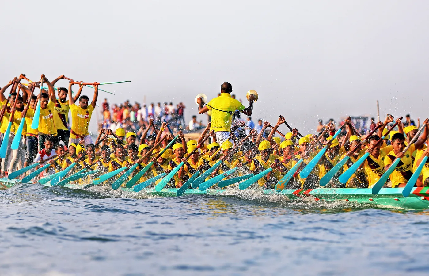 Rowers in yellow driving a racing boat forward