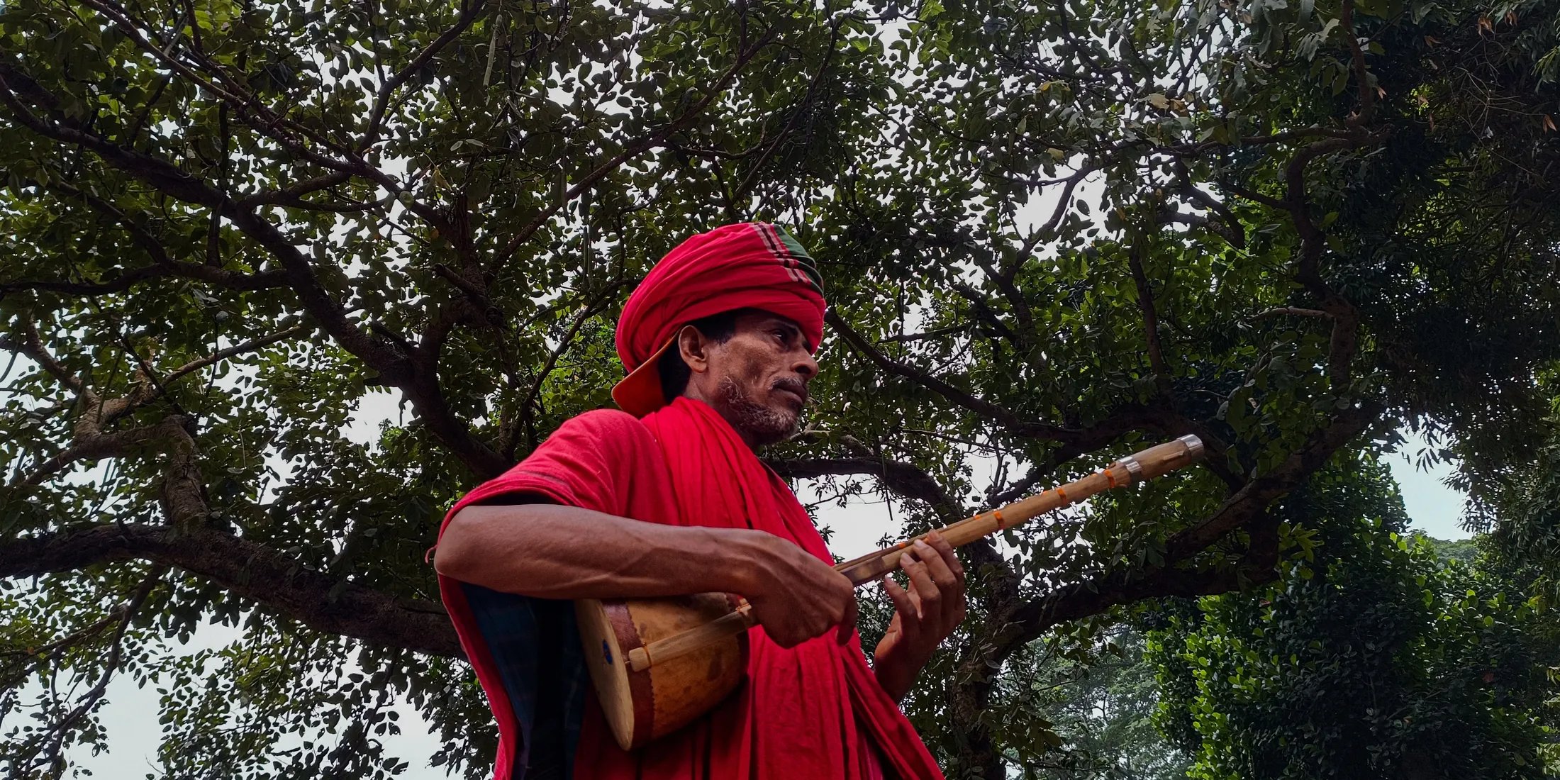 A Baul singer performing under a tree
