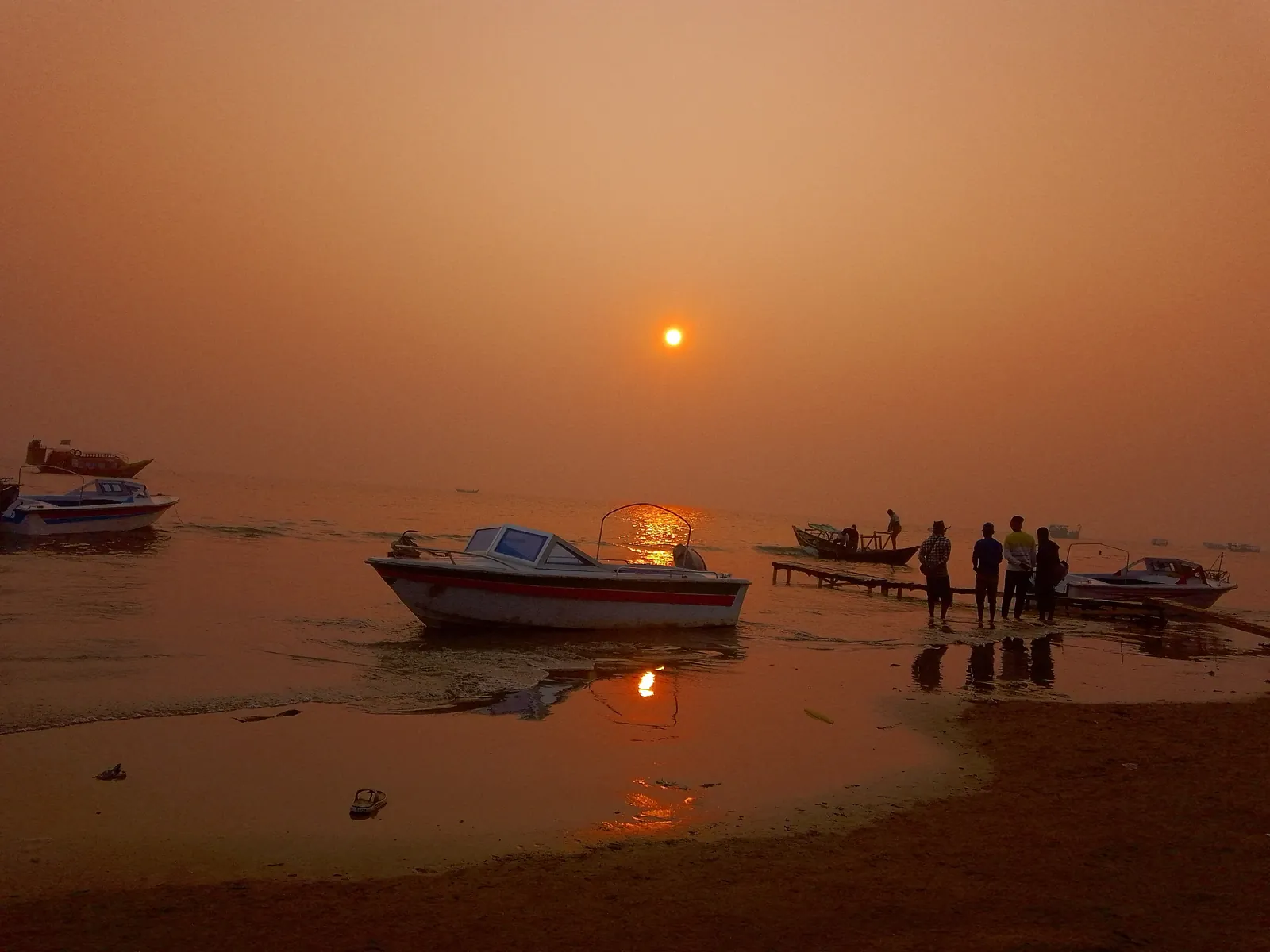 Fishing boats on the sand at Kuakata under an orange sunset